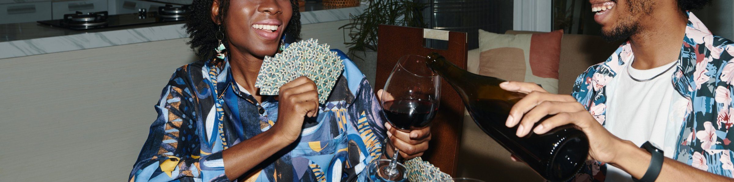 Friends playing cards while one pours red wine